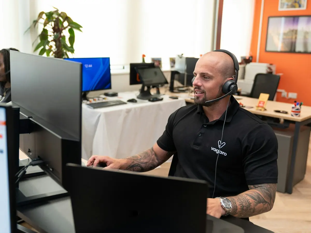 A customer support representative wearing a headset at a computer.