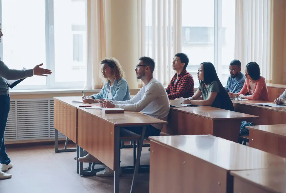 A teacher speaking with students in a bright classroom.
