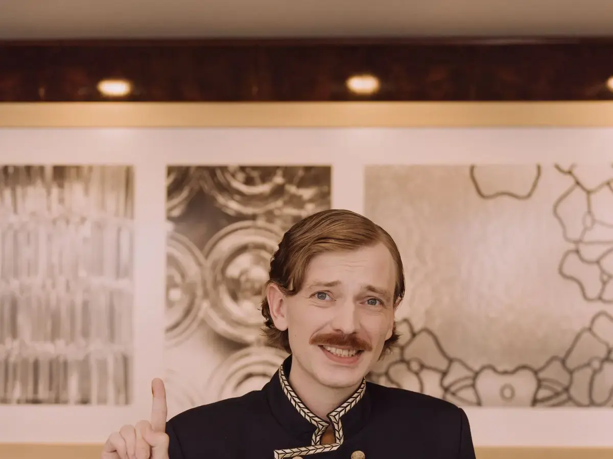 A hotel receptionist welcoming a guest at the front desk.