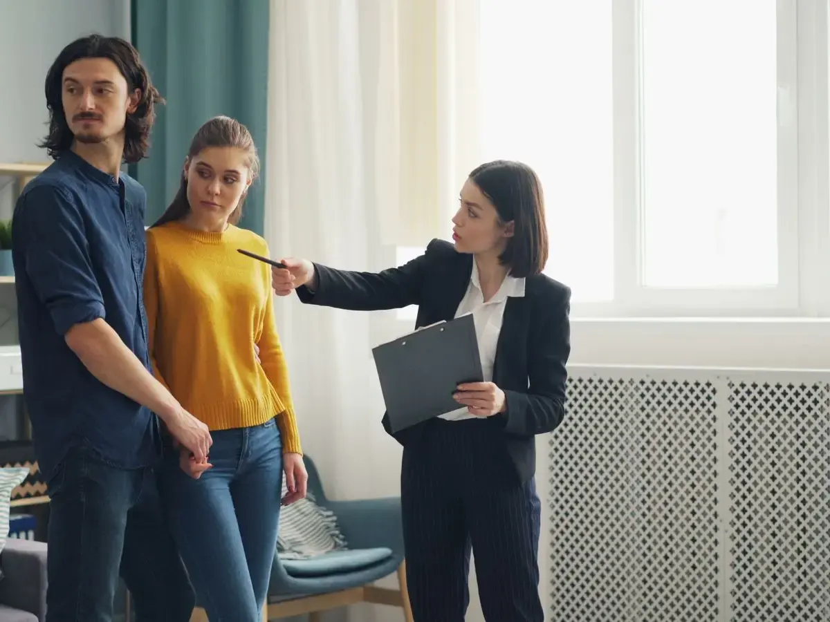 A property agent showing a bright home to a couple.