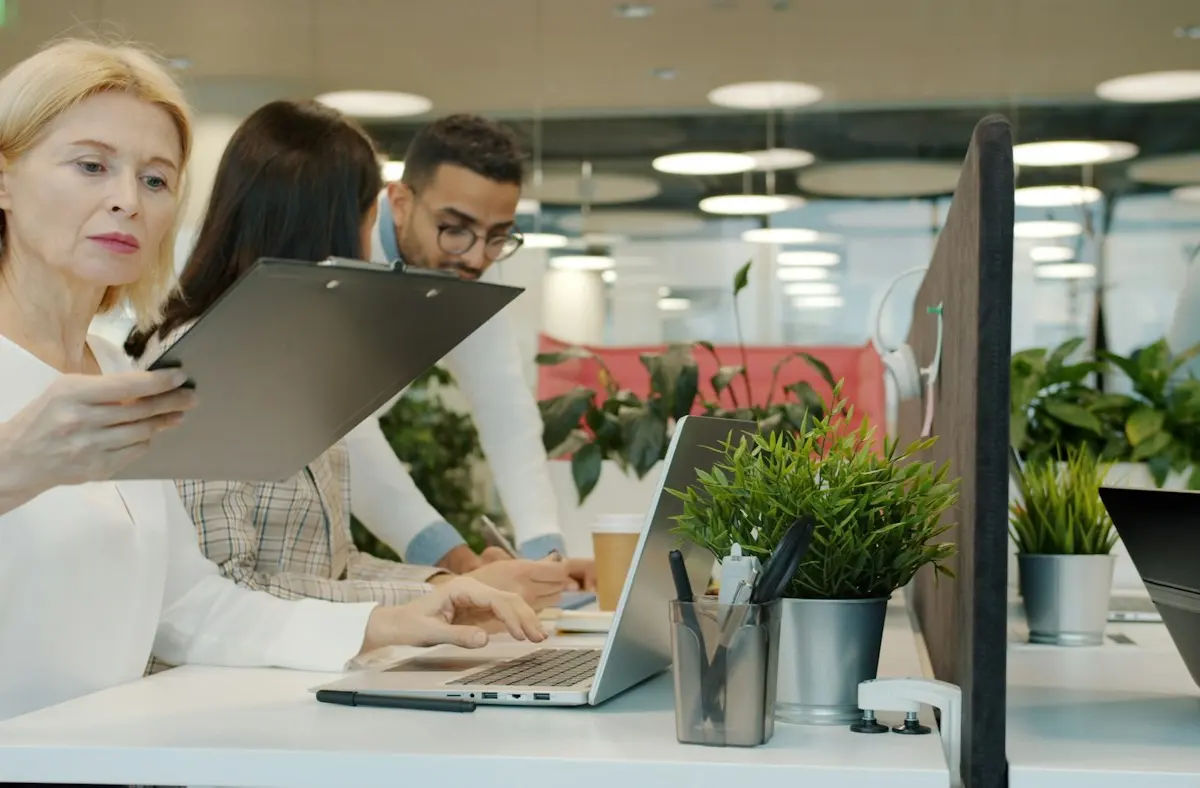 Colleagues sharing a laptop during an office discussion.